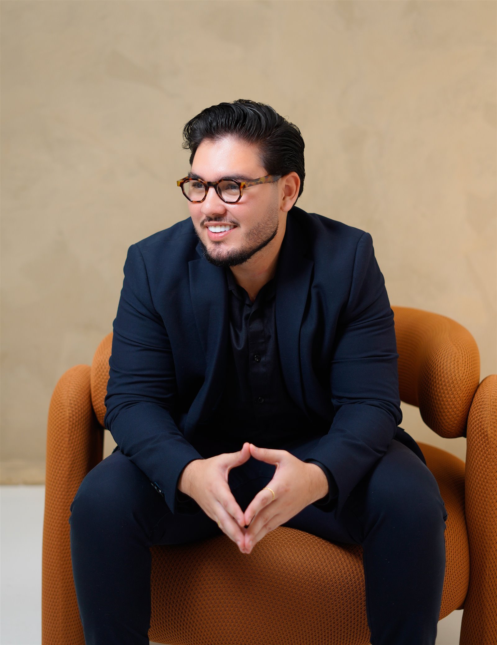 Dr. Lucas Andrade sentado, sorrindo, com as mãos entrelaçadas.